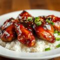 Close-up of juicy bourbon chicken glazed in a sweet and savory sauce, served over rice.